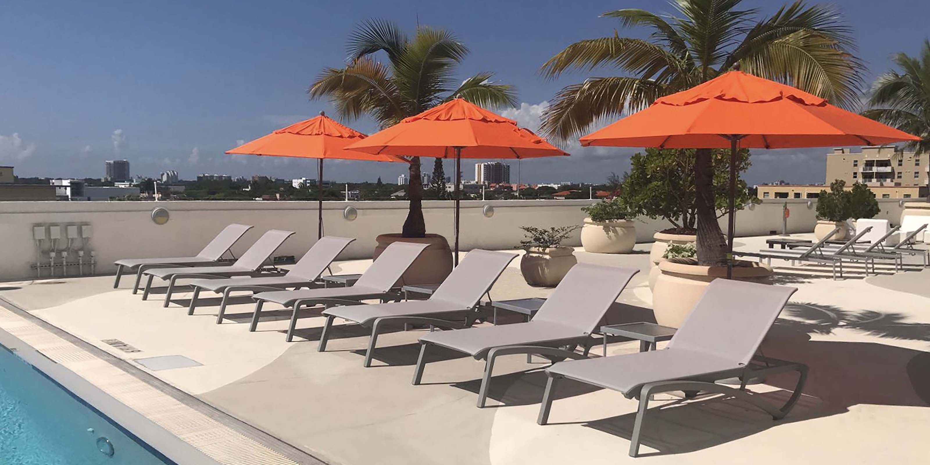 Umbrella Poles combined with bases anchor umbrellas above chaise lounges at this poolside resort