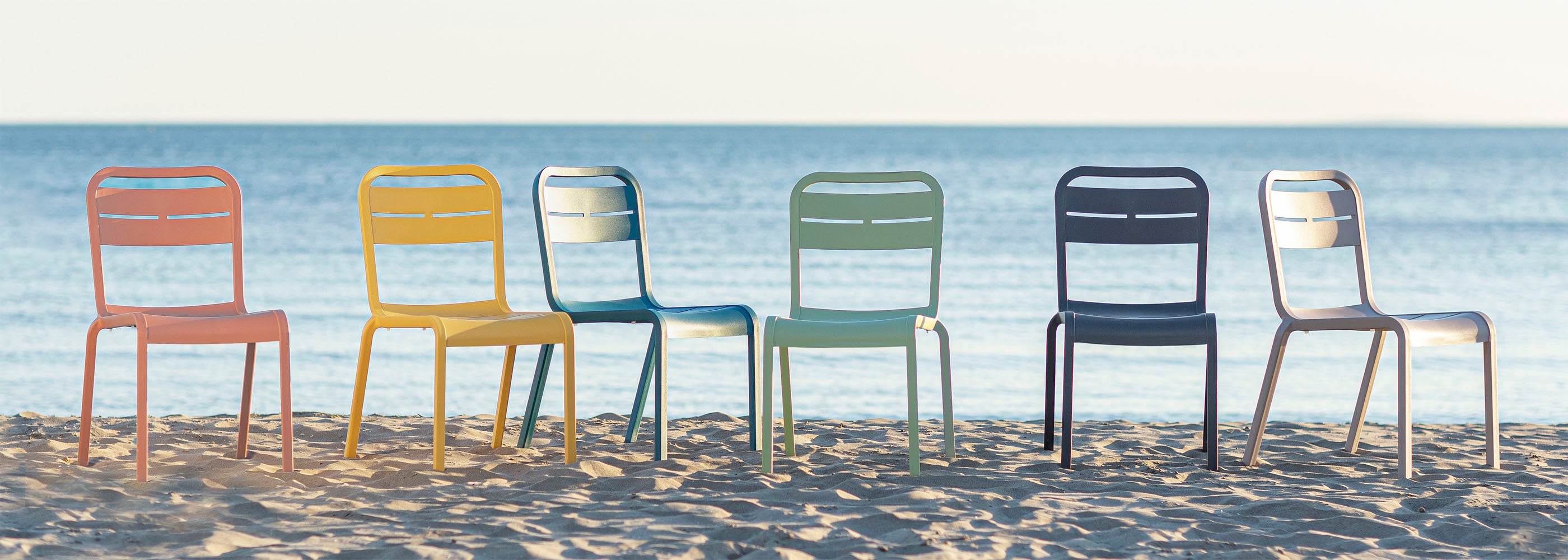 A row of Cannes chairs sit on a beach overlooking the skyline of the ocean