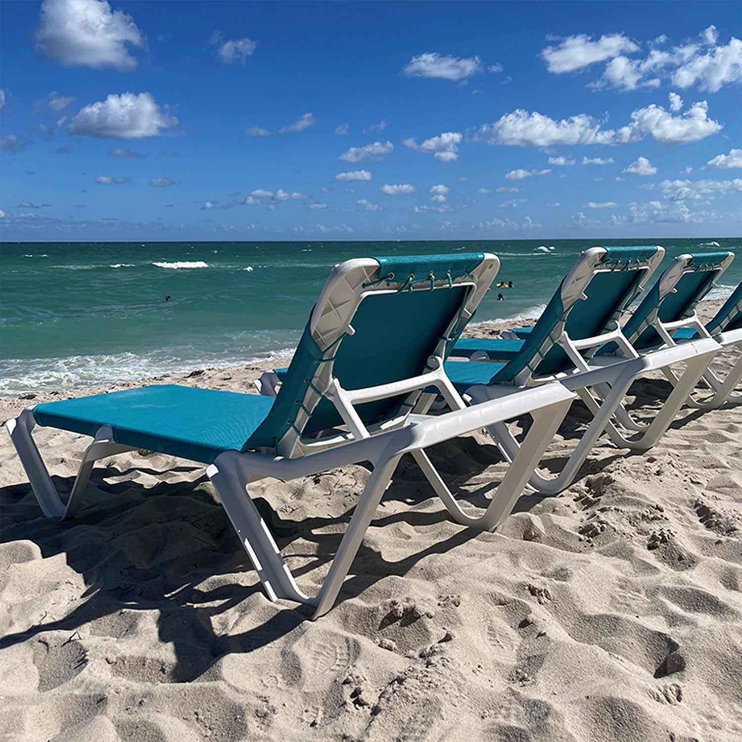 Nautical Chaise Lounges in a row looking out to the ocean from the beach