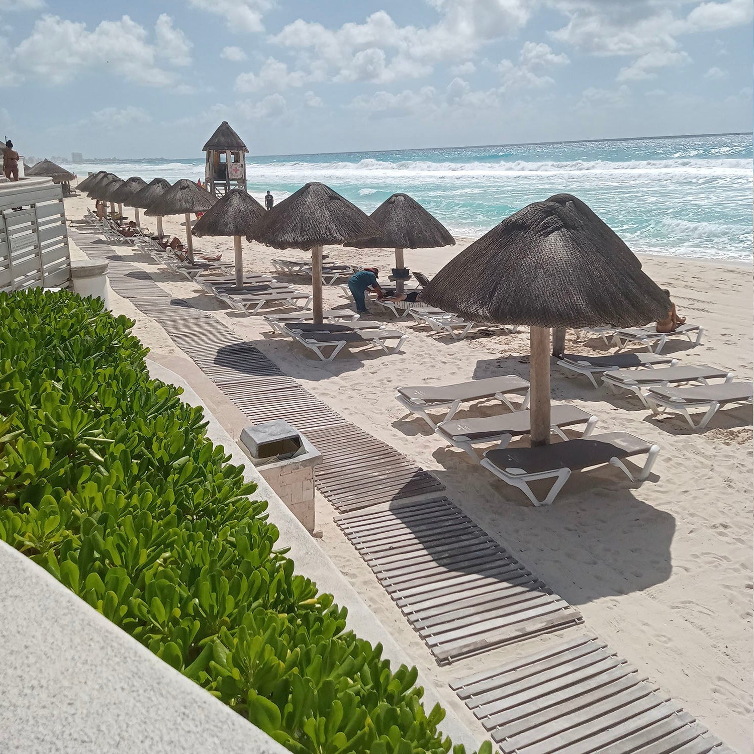 A beautiful view on the blue ocean and chaise lounges lined up on the beach.