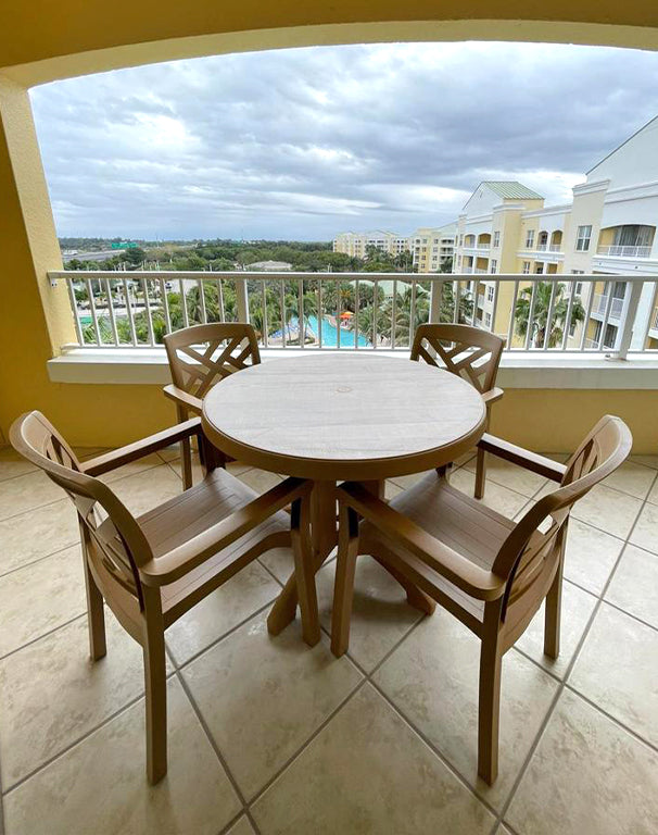 A Grosfillex Aquaba Table and Sanibel Armchairs overlook the pool on the balcony at Vacation Village
