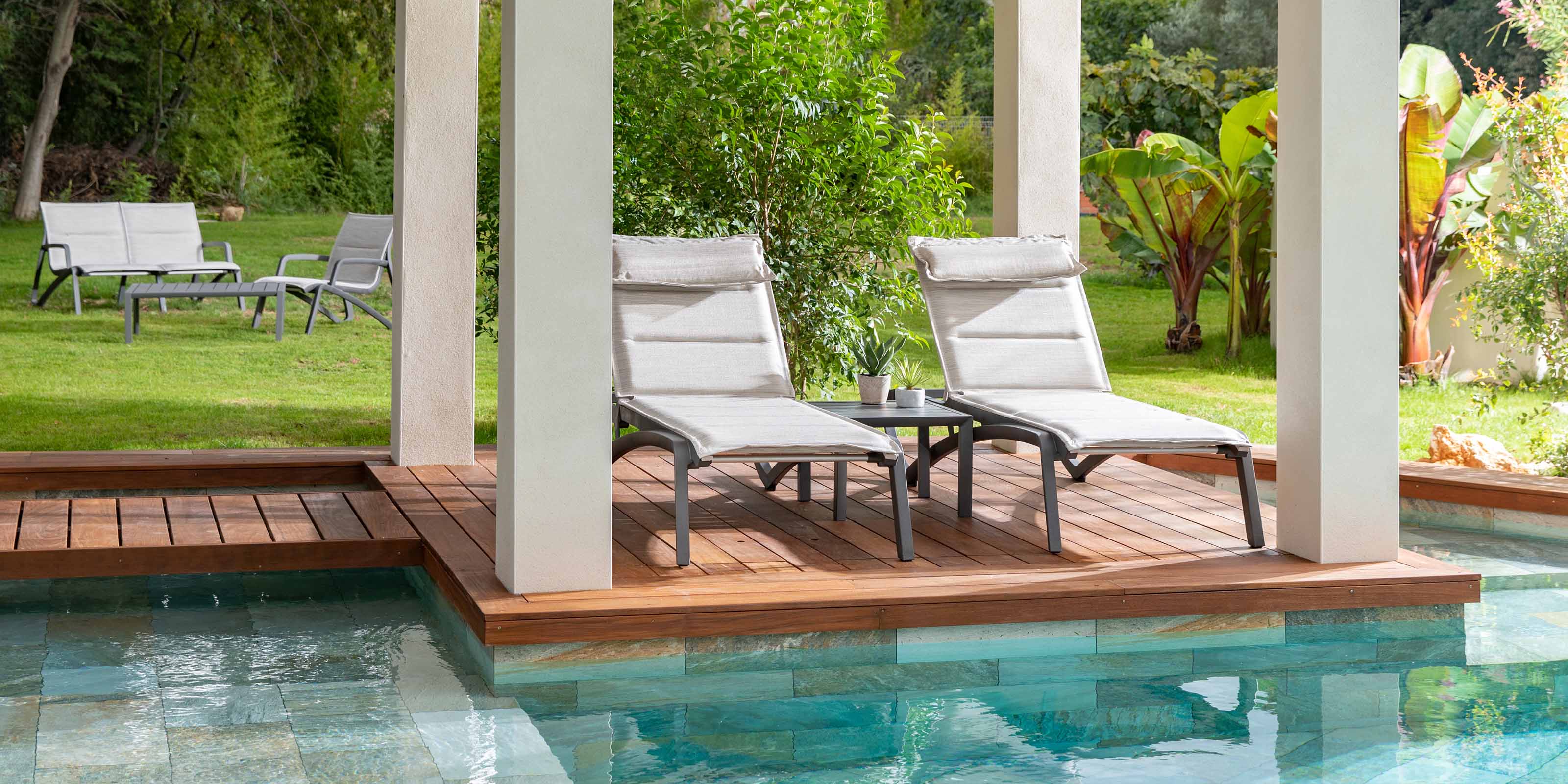 Capture the essence of tranquility in this poolside scene featuring a collection of stylish chaises and lounge chairs, including the inviting Sunset Comfort Chaise. As the sun sets, bask in the serene glow of comfort and elegance.