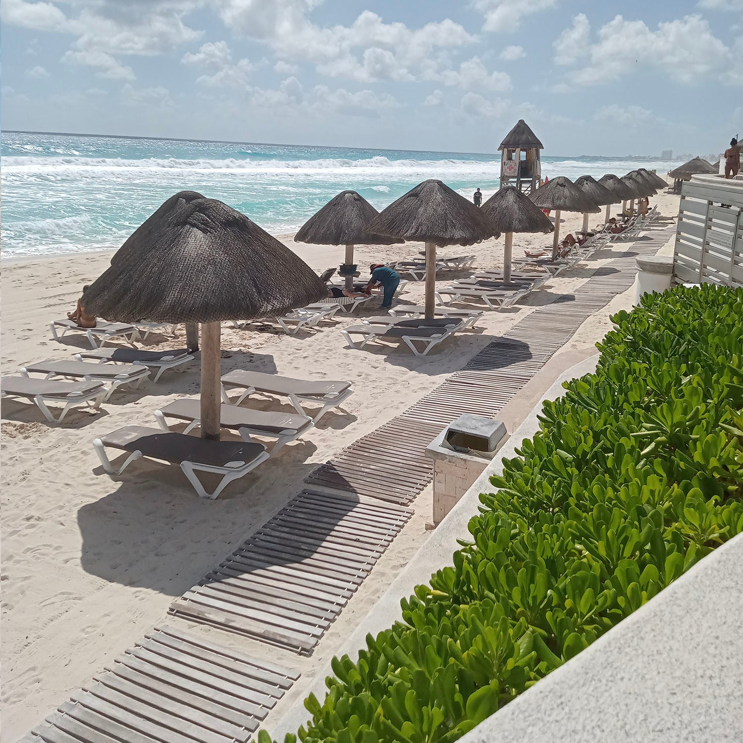 A beautiful view on the blue ocean and chaise lounges lined up on the beach.